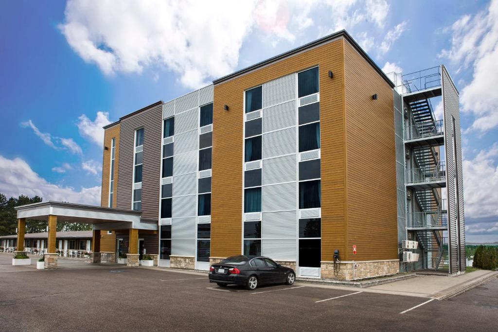 auf einem Parkplatz vor einem Gebäude geparkt in der Unterkunft Hotel De La Borealie in Saint-Félicien