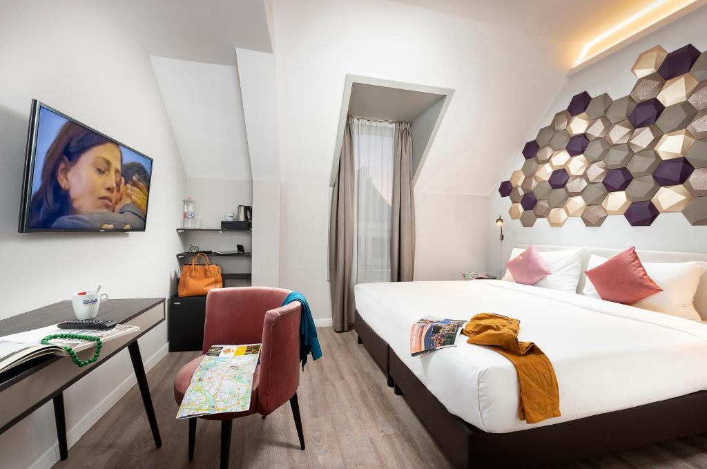 ブダペストにあるThree Corners Hotel Artのベッド、デスク、椅子が備わるホテルルームです。