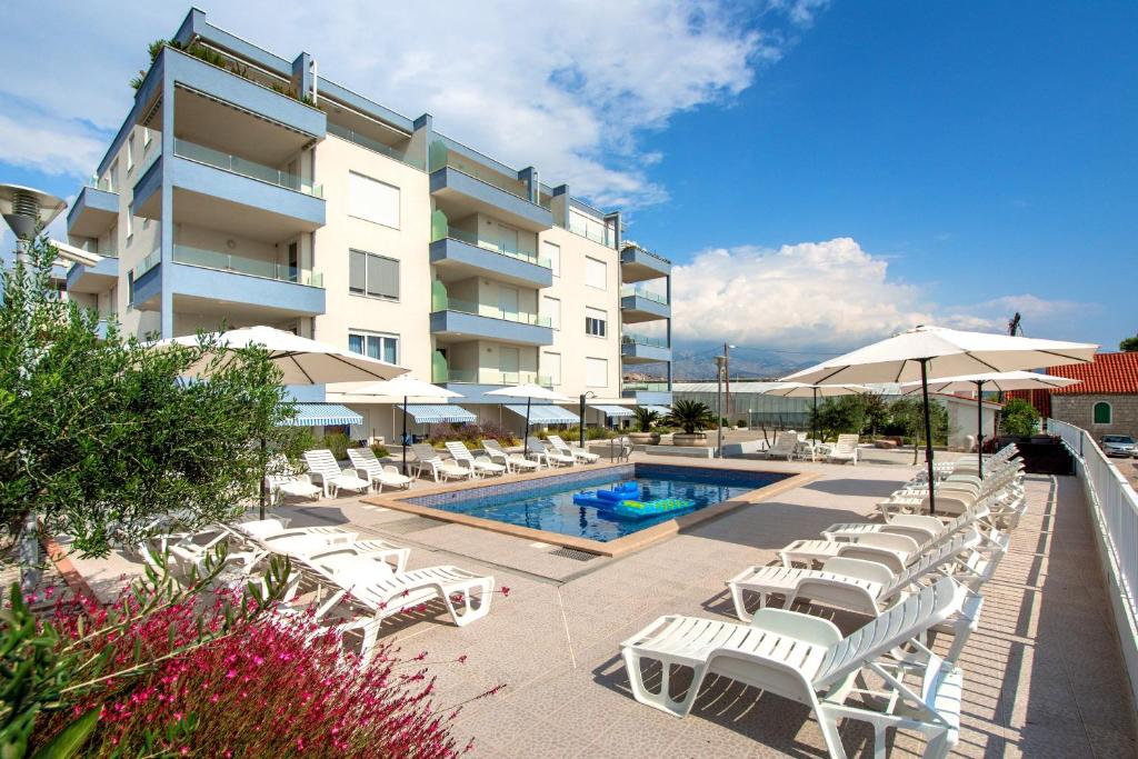een zwembad met stoelen en parasols naast een gebouw bij Apartments Kamelija in Split