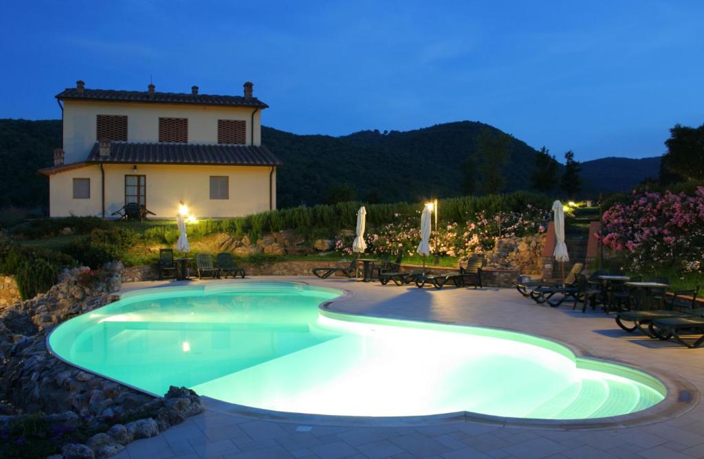 una piscina con una casa en el fondo en La Grotta dell'Eremita, en Gambassi Terme