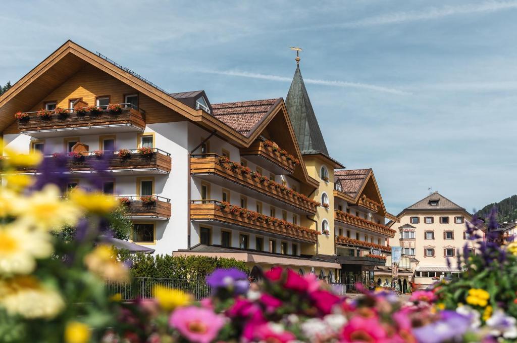 un bâtiment avec des fleurs devant lui dans l'établissement Hotel Oswald, à Selva di Val Gardena