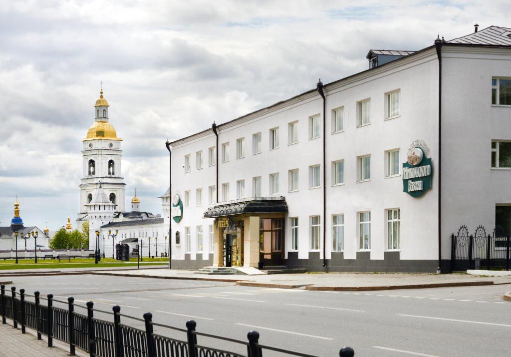 a street in front of a white building with a clock tower at Hotel Siberia in Tobolsk