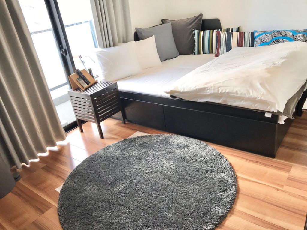 a bedroom with a bed with a rug and a window at Local Hakata apartment No8 in Fukuoka