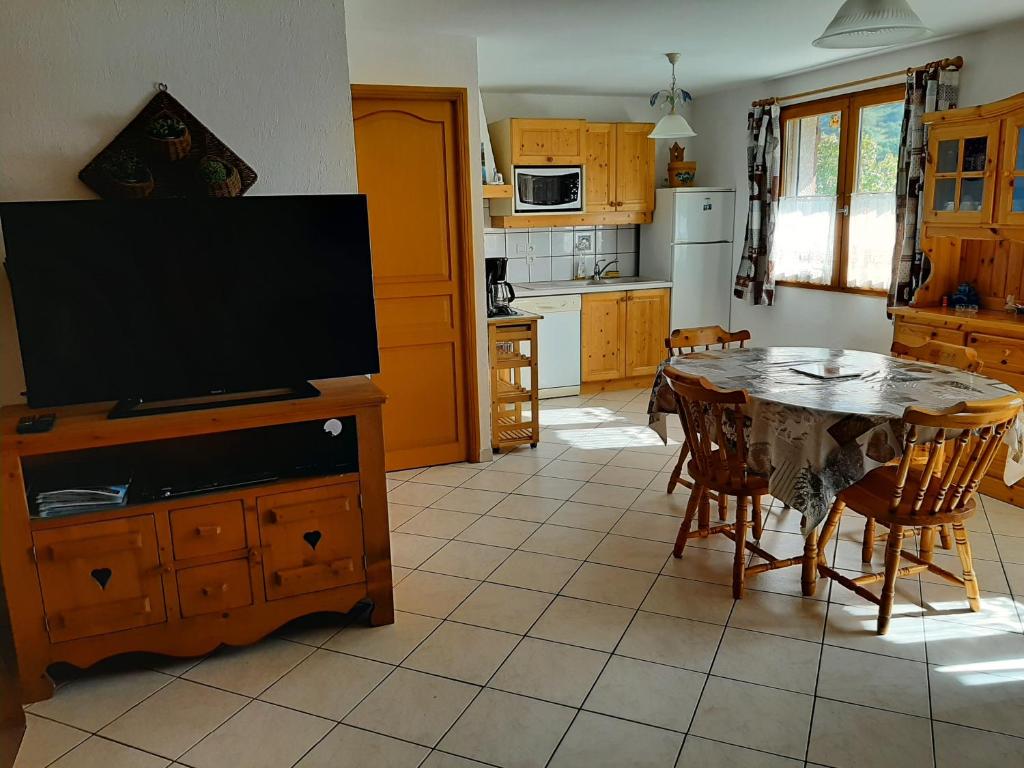eine Küche mit einem TV und einem Tisch mit Stühlen in der Unterkunft Gîte Les Grands Champs in Bellentre