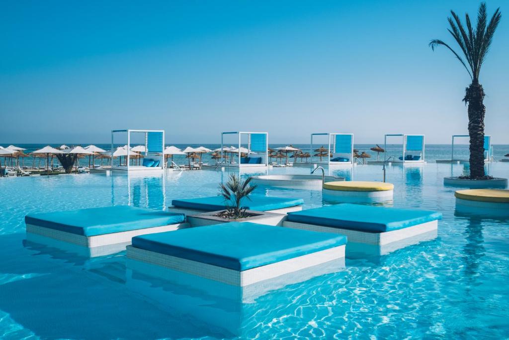 a hotel swimming pool with blue and white beds at Iberostar Selection Kuriat Palace in Monastir