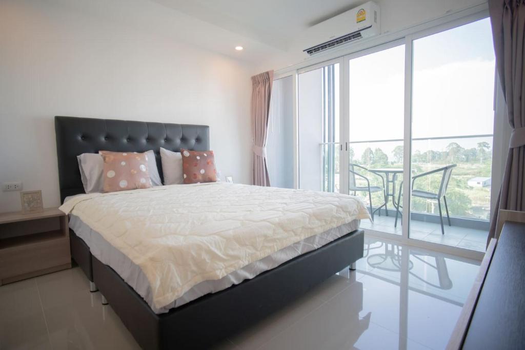um quarto com uma cama grande e uma varanda em Cozy SeaSaran em Sattahip