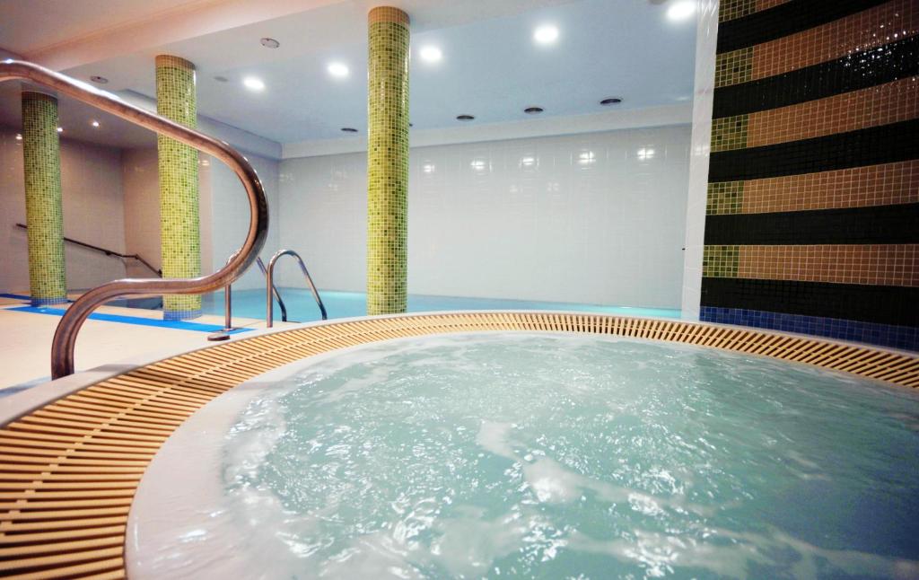 eine Whirlpool-Badewanne in einem Zimmer mit Säulen in der Unterkunft Bursztyn Spa in Kołobrzeg