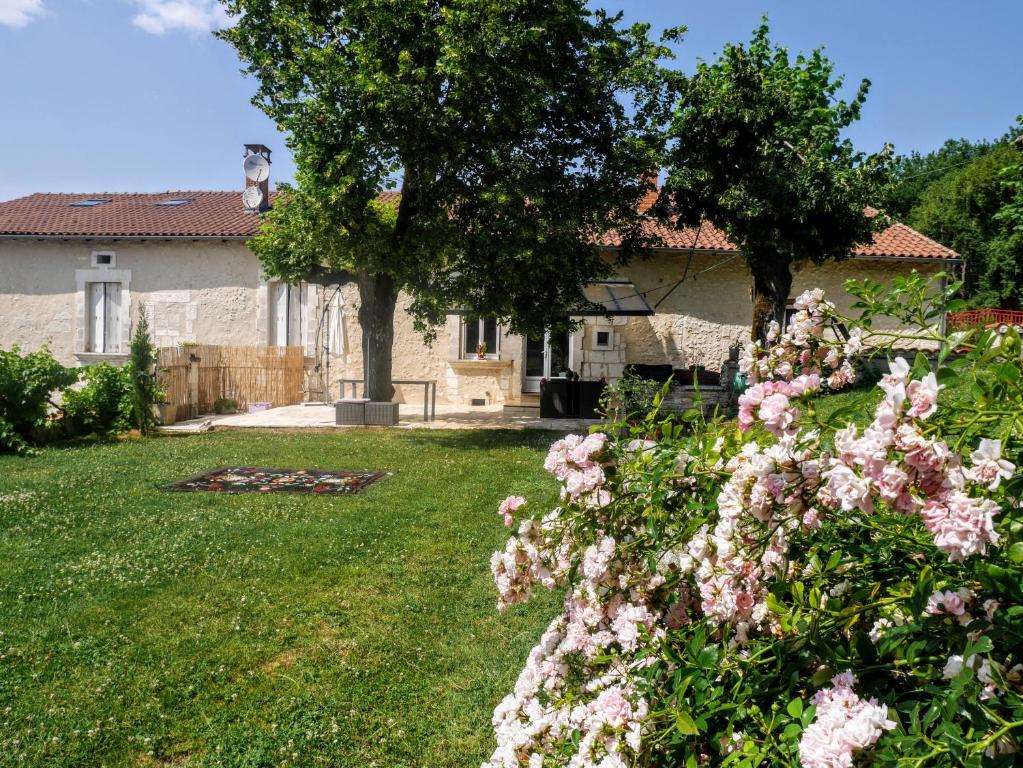 une maison avec une cour ornée de fleurs roses dans l'établissement Gîtes Chez "hygge en périgord" avec piscine chaufffée - 1 gîte de 6 à 12 personnes et 1 gîte de 2 personnes, à Léguillac-de-Lauche