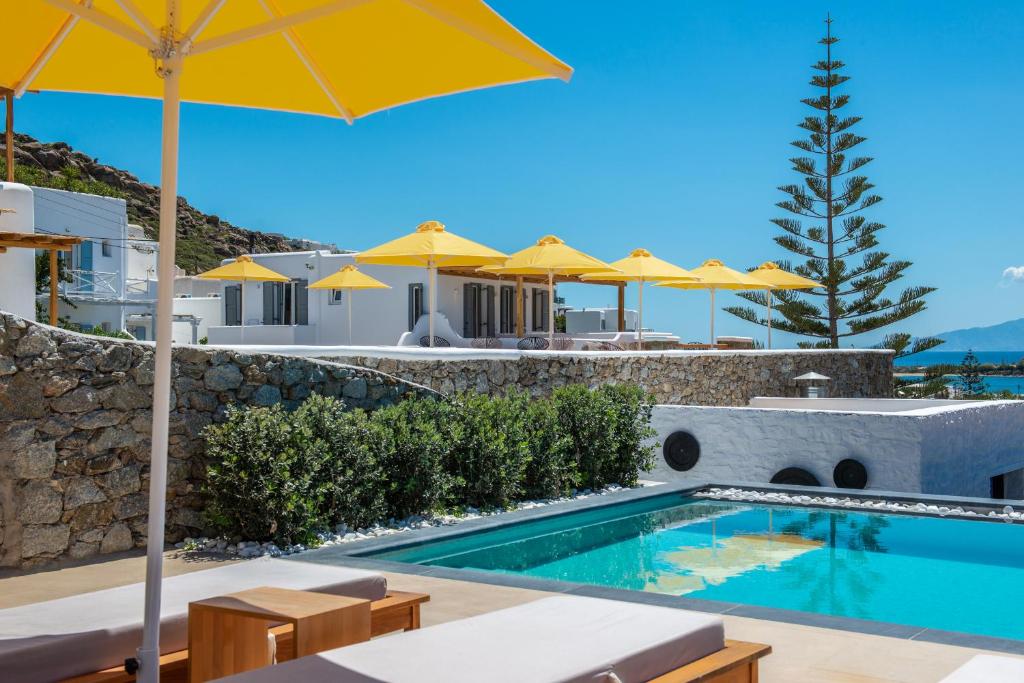 a villa with a swimming pool and yellow umbrellas at Artemoula's Studios in Platis Gialos