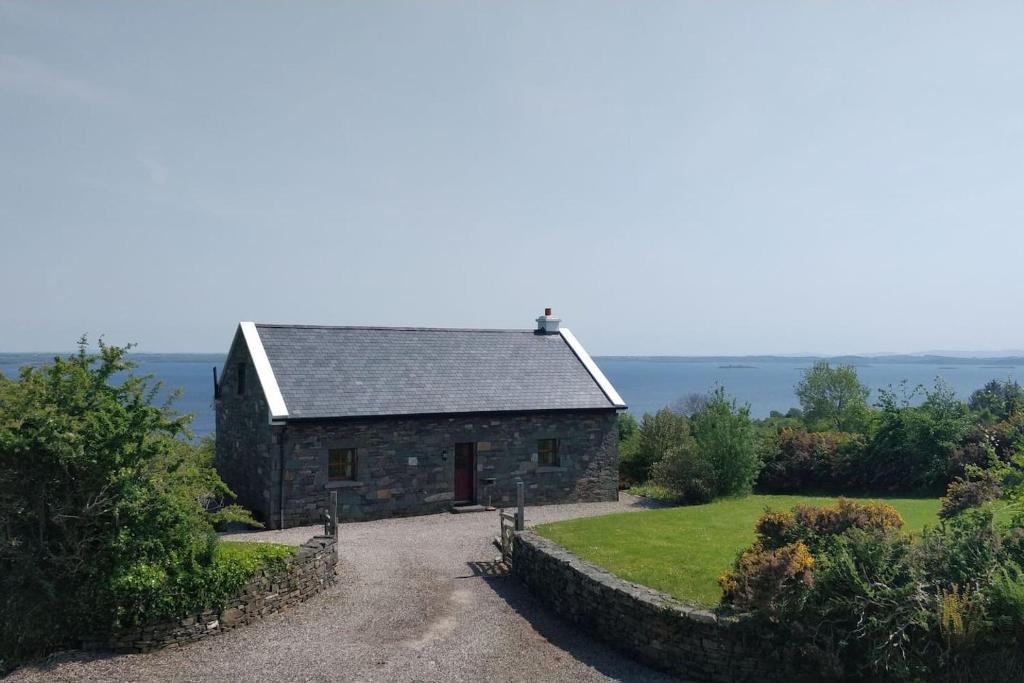 una vecchia casa in pietra con un vialetto di ghiaia di Groff Cottage a Toormakeady