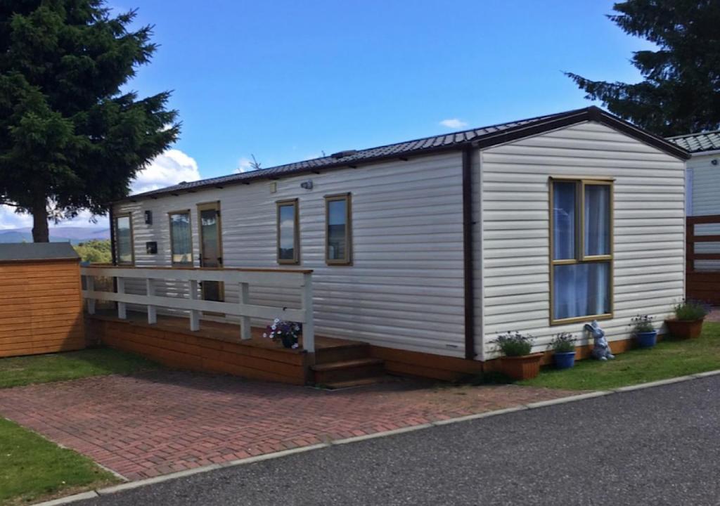 une petite maison blanche située au-dessus d'une allée. dans l'établissement 22 Aimie Lodge, à Boat of Garten