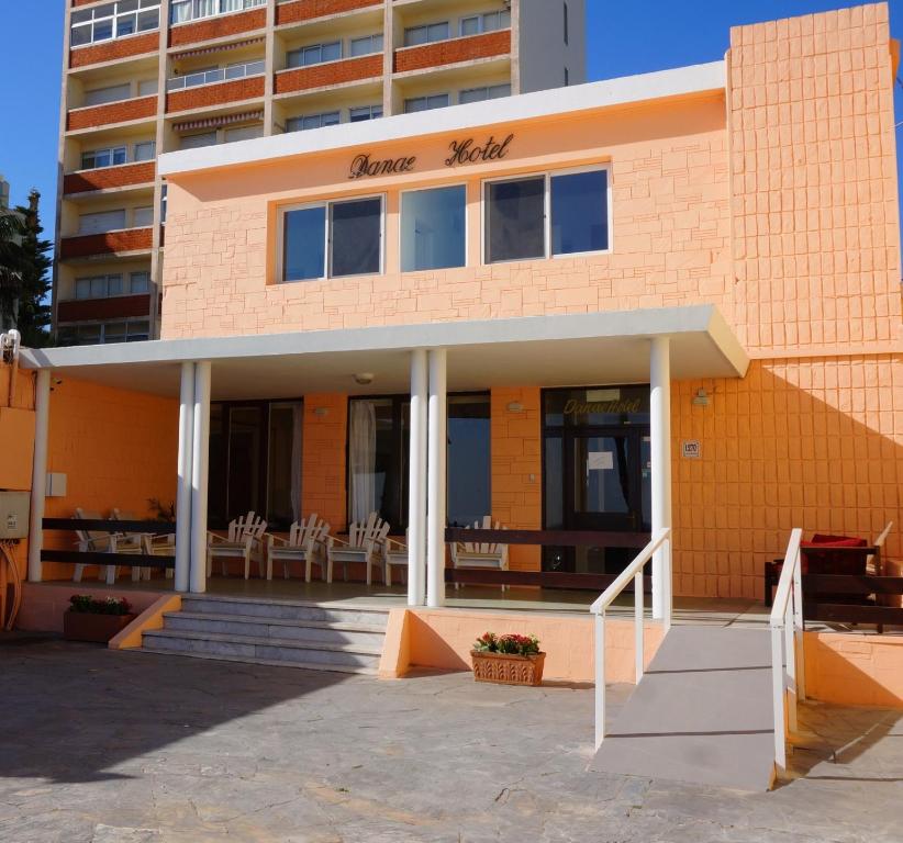 um edifício de tijolos laranja com mesas e cadeiras à frente em Hotel Danae em Piriápolis