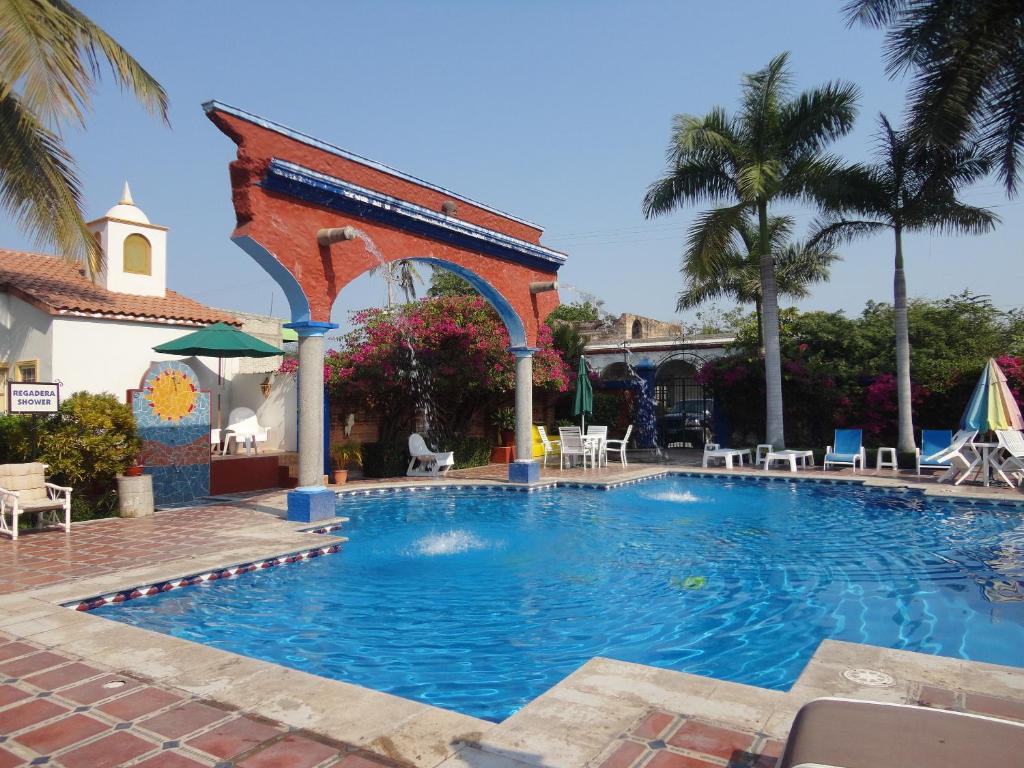 una gran piscina con un arco y sillas en Hotel Hacienda Flamingos, en San Blas