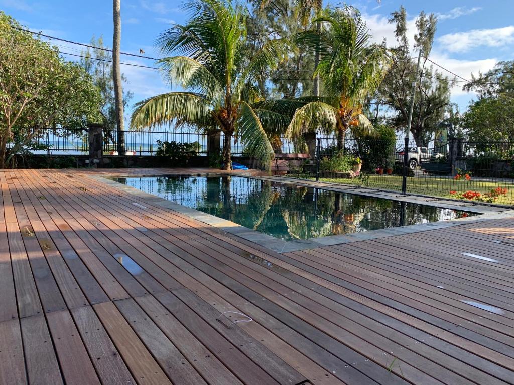 a swimming pool in a park with a wooden deck at The Beach House Rodrigues in Rodrigues Island