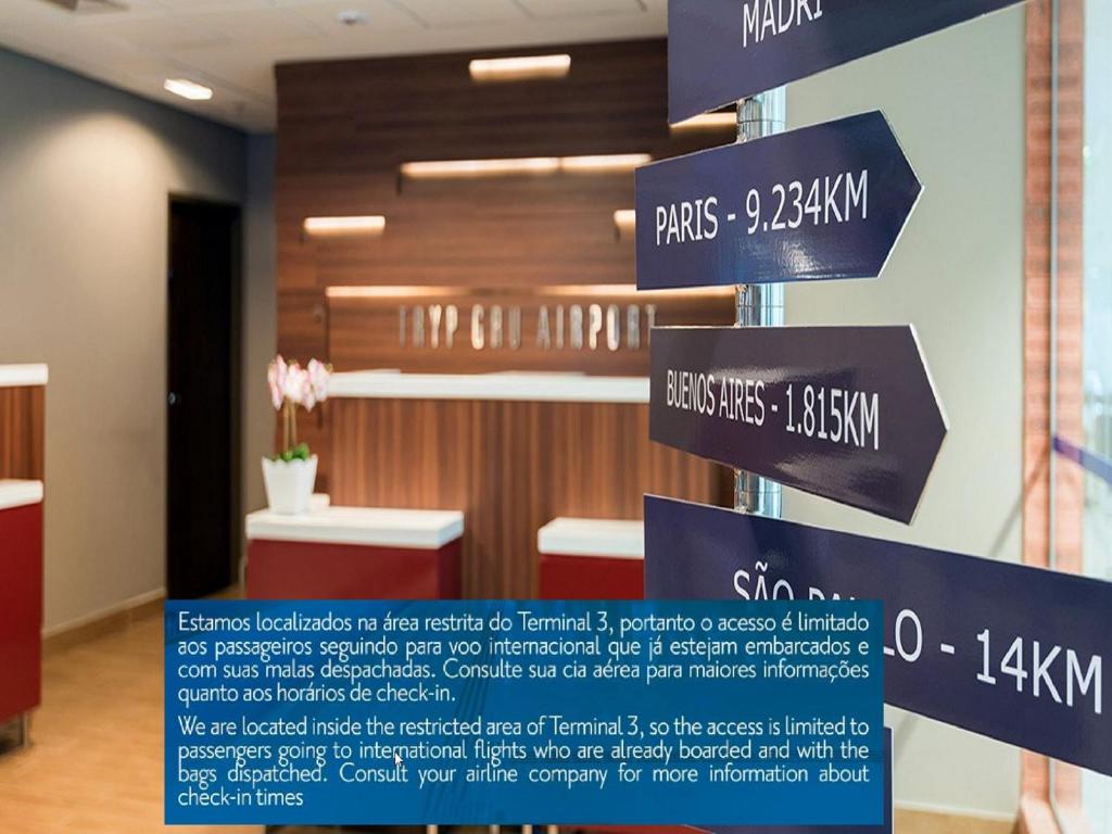 a sign in a room with signs on a pole at TRYP BY WYNDHAM São Paulo Airport - Hotel de Transito Terminal 3 -Lado Ar - Área restrita á passageiros já embarcados - Piso 1 in Guarulhos