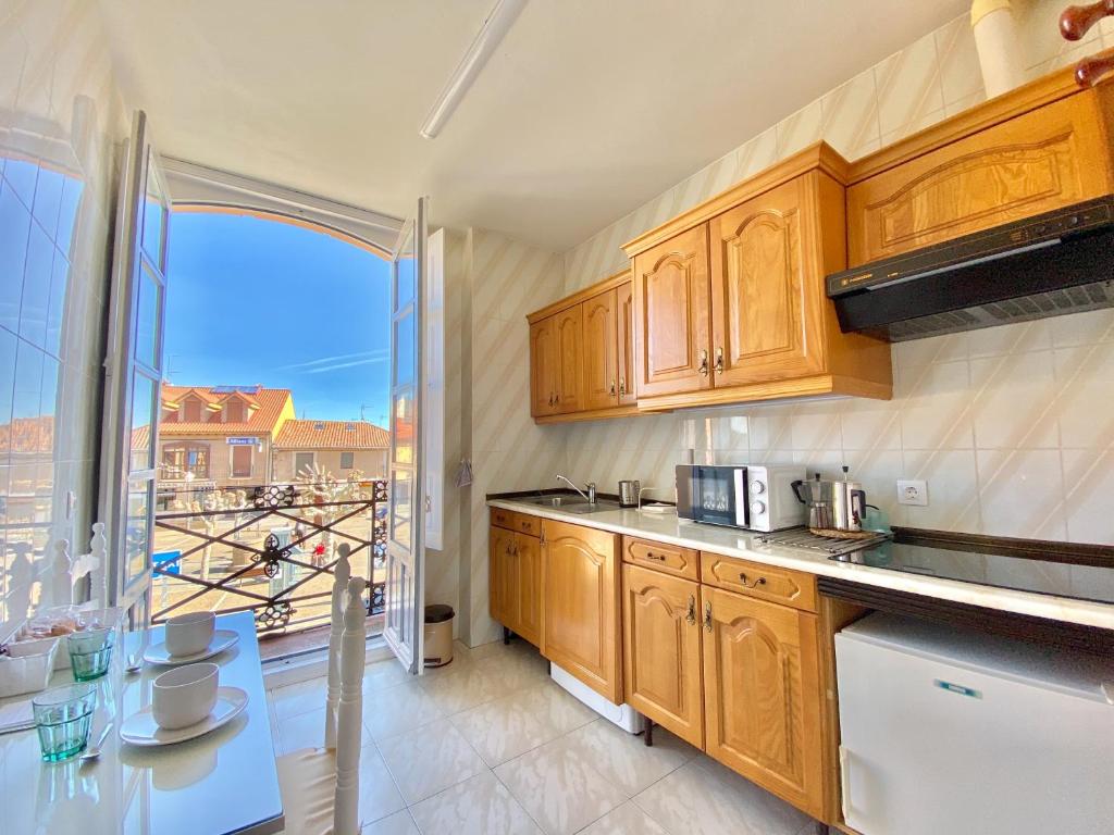 a kitchen with wooden cabinets and a large window at La Casa de Mansilla in Mansilla de las Mulas