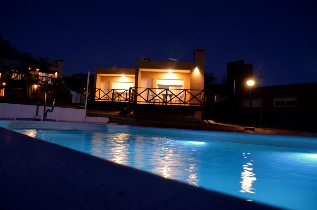 - une piscine en face d'une maison la nuit dans l'établissement ARROYO SUITE HOUSE, à Mina Clavero