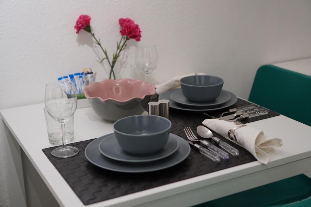 einen Tisch mit zwei Tassen und Tellern und eine Vase mit Blumen in der Unterkunft London Queen Park Apartments in London