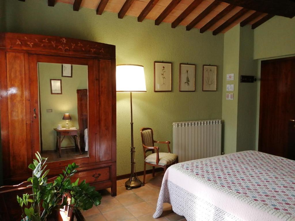 a bedroom with a bed and a lamp and a chair at Antica Fattoria del Colle in Deruta