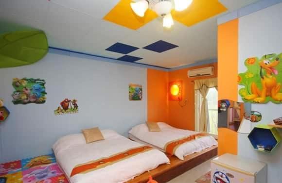 冬山鄉的住宿－101親子溜滑梯民宿 ，橙色墙壁客房的两张床