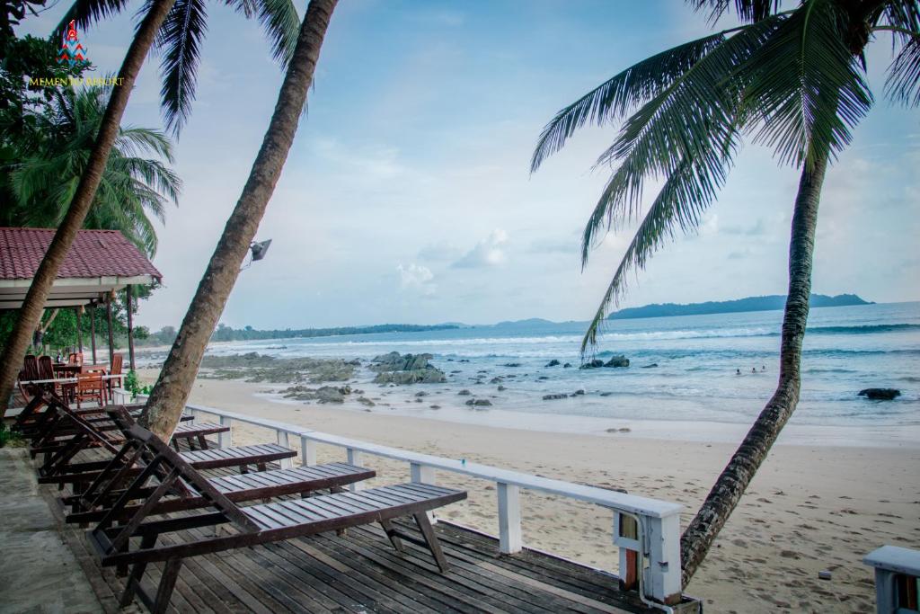 a row of benches on a beach with palm trees at Memento Resort in Ngapali