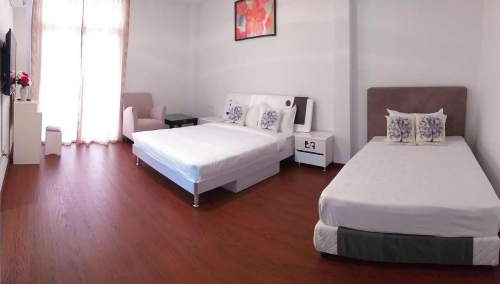 a bedroom with two beds and a wooden floor at Coconut Bay Lodge in Bandar Seri Begawan