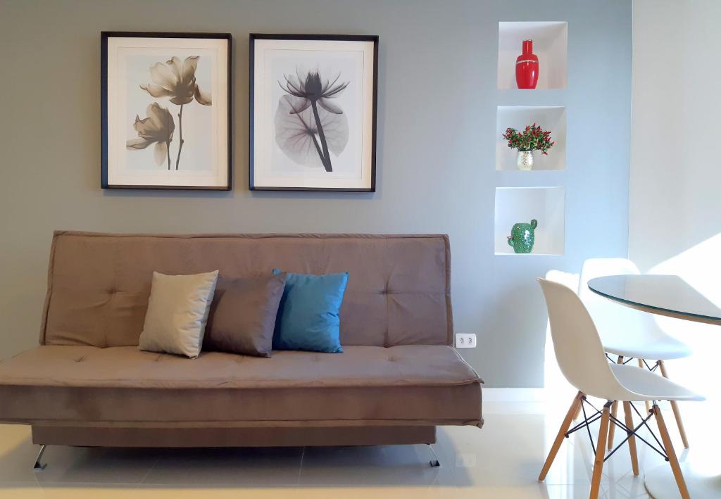 eine Couch in einem Wohnzimmer mit drei Bildern an der Wand in der Unterkunft Royal Ibirapuera Park - Flat in São Paulo