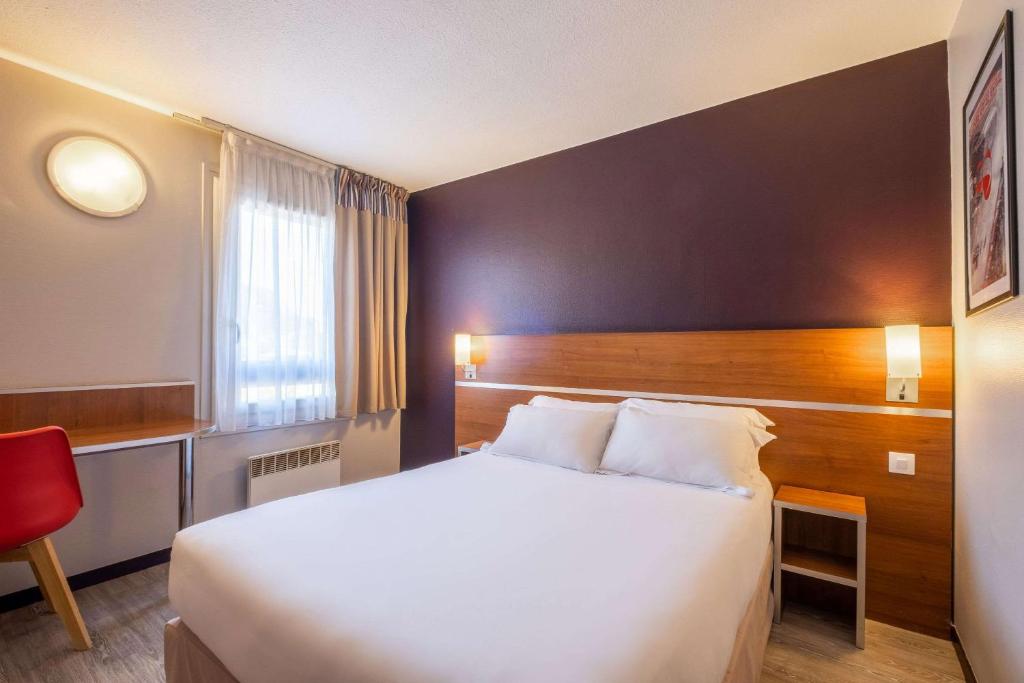 een hotelkamer met een groot bed en een rode stoel bij Comfort Hotel Linas - Montlhery in Montlhéry