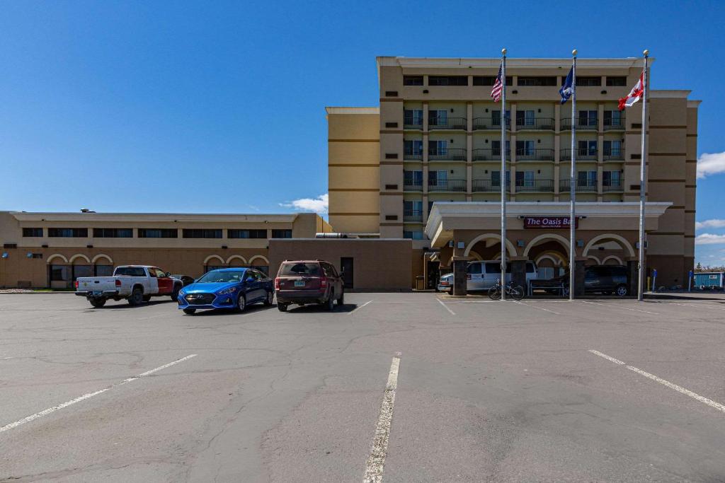 un grand bâtiment avec des voitures garées dans un parking dans l'établissement Clarion Hotel Convention Center, à Minot