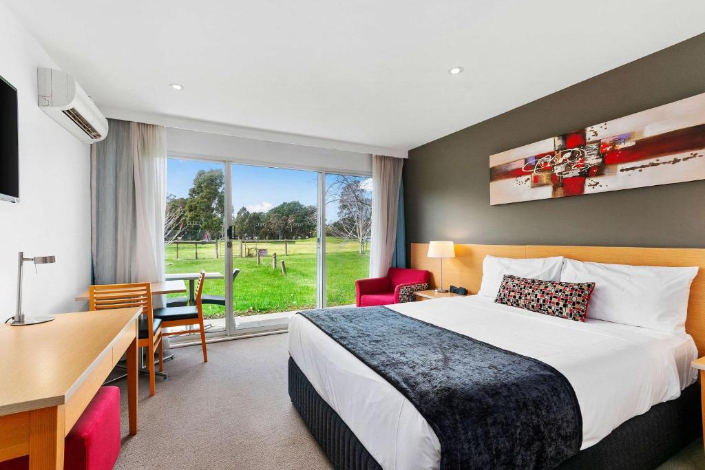 a hotel room with a bed and a desk and a window at Quality Inn & Suites Traralgon in Traralgon