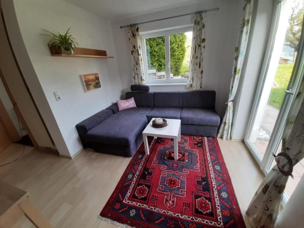 uma sala de estar com um sofá azul e um tapete vermelho em Ferienapartment Prantner em Grins