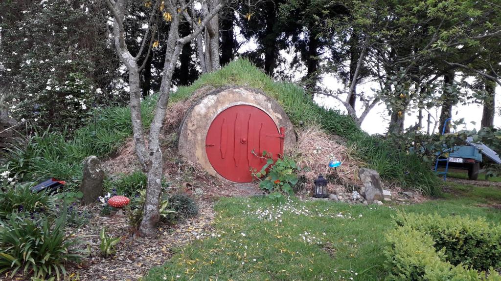einen Garten mit einer roten Tür im Gras in der Unterkunft Kaimai Sunset Bed & Breakfast in Matamata