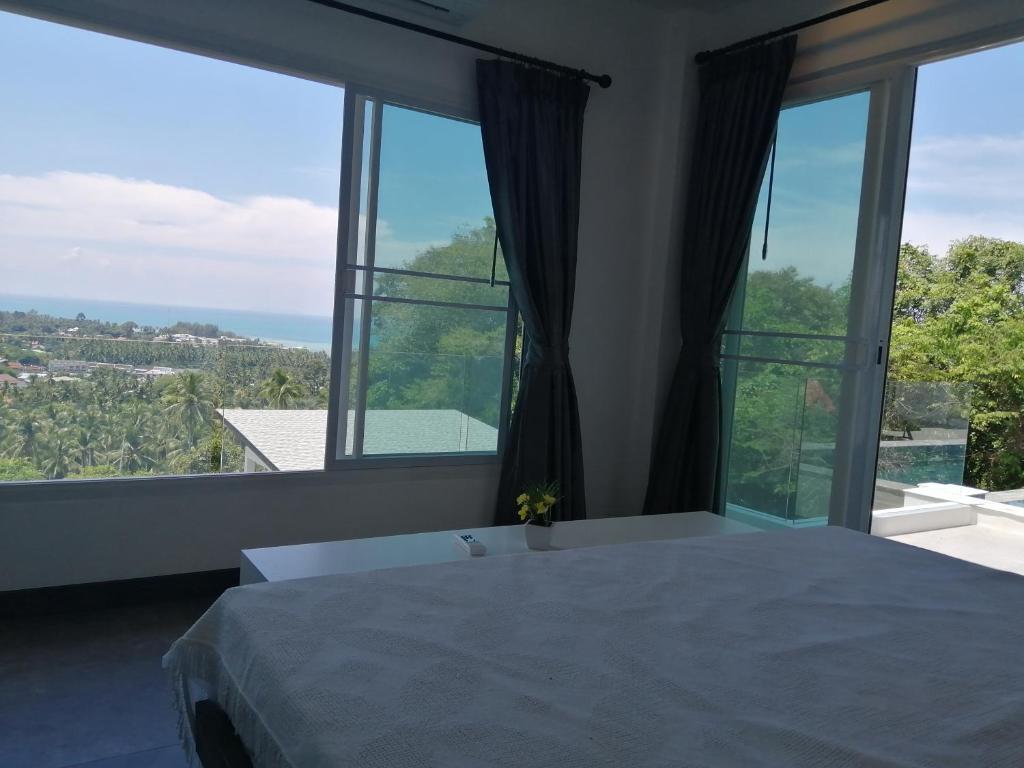 Un dormitorio con una cama y grandes ventanales. en Pearl Villa, en Nathon