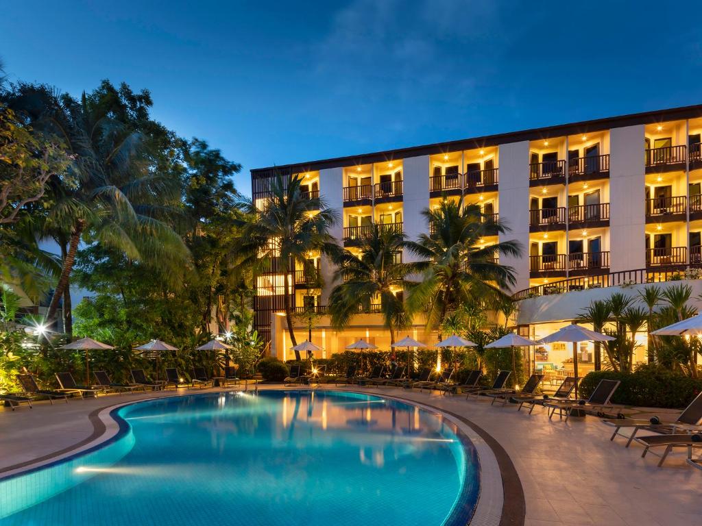 a hotel with a swimming pool in front of a building at Ibis Phuket Patong in Patong Beach