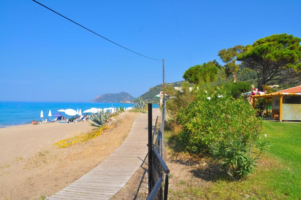 a wooden path leading to a beach with a house at Beachfront holiday House “yannis” on Agios Gordios beach in Corfu in Agios Gordios