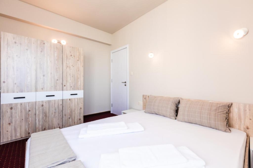 a bedroom with a large white bed and wooden cabinets at Guest House Theona in Obzor