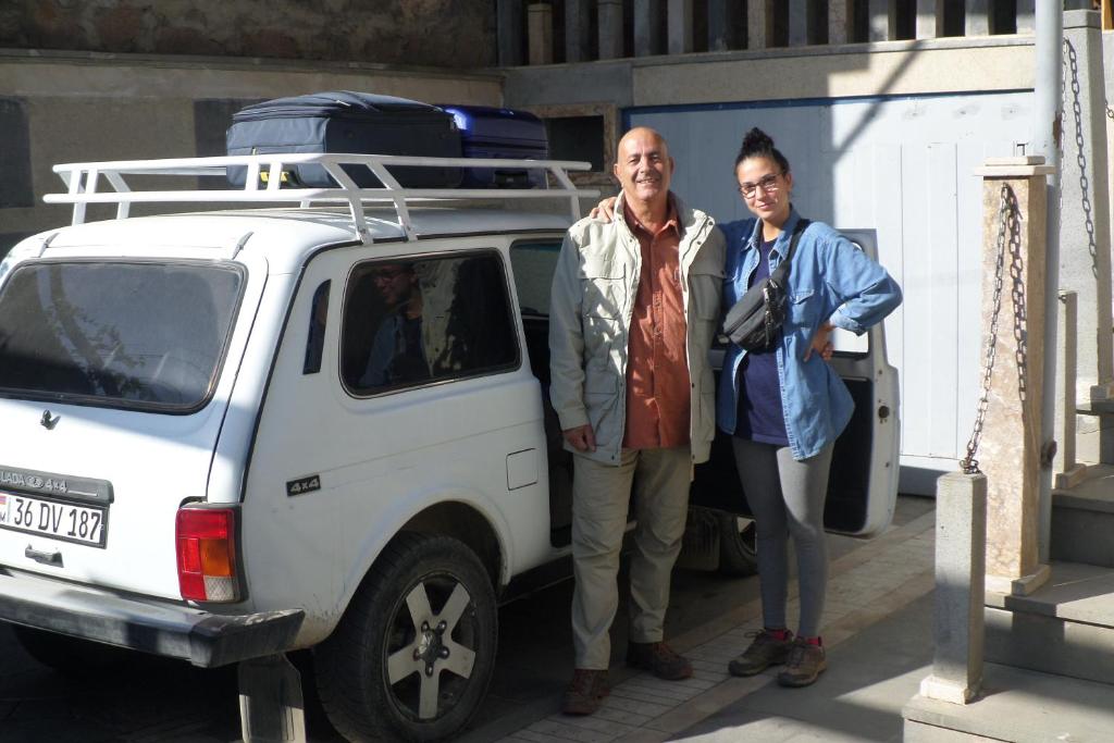 un homme et une femme debout à côté d'un véhicule blanc dans l'établissement Spandaryan House, à Yeghegnadzor