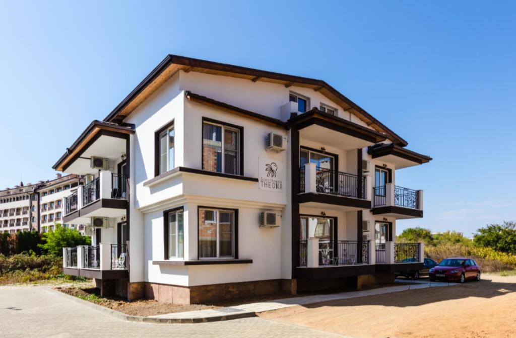 a white house with a car parked in front of it at Guest House Theona in Obzor