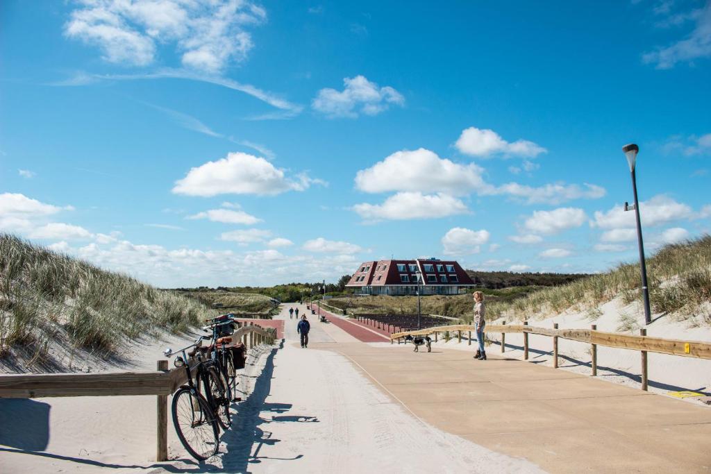 un vélo garé sur un pont au-dessus de la plage dans l'établissement Strandhotel Buren aan Zee, à Buren