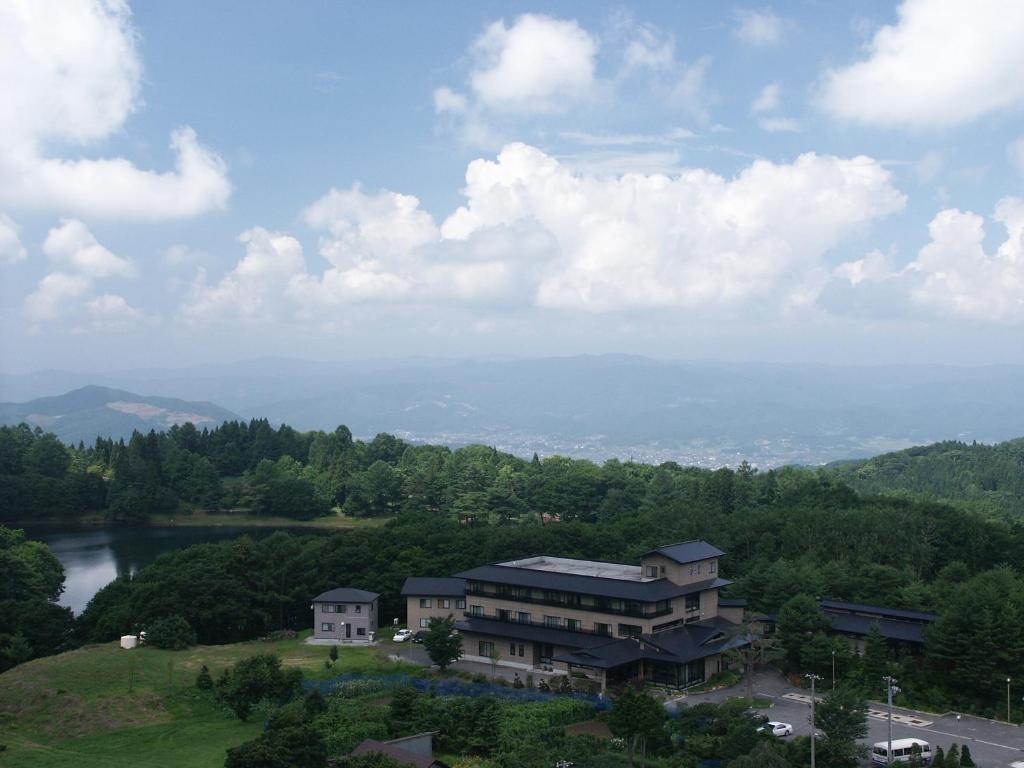une maison au sommet d'une colline avec un lac dans l'établissement Iwashimizu Ryori no Yado Kinosato, à Zao Onsen