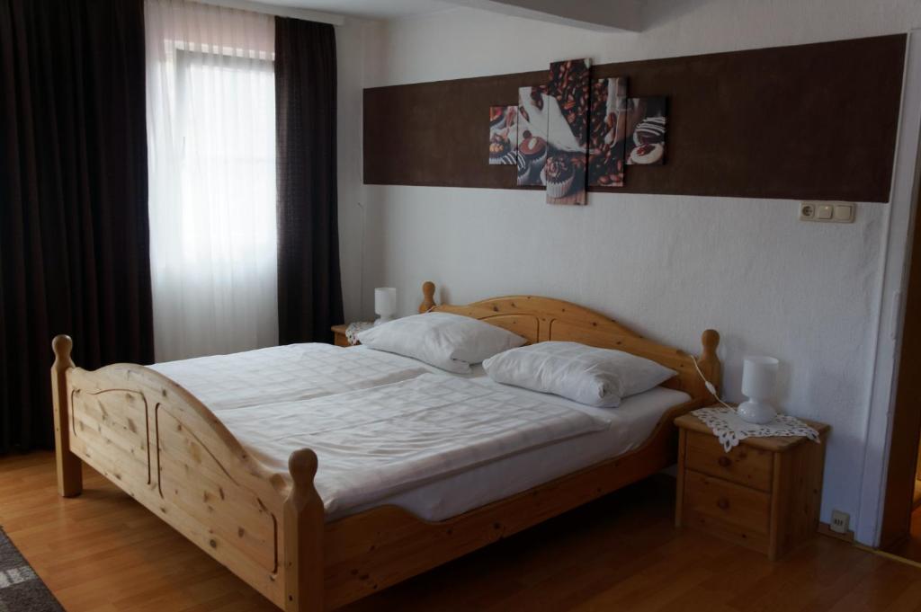 1 dormitorio con cama de madera con sábanas y almohadas blancas en Pension Burger B&B, en Weibersbrunn