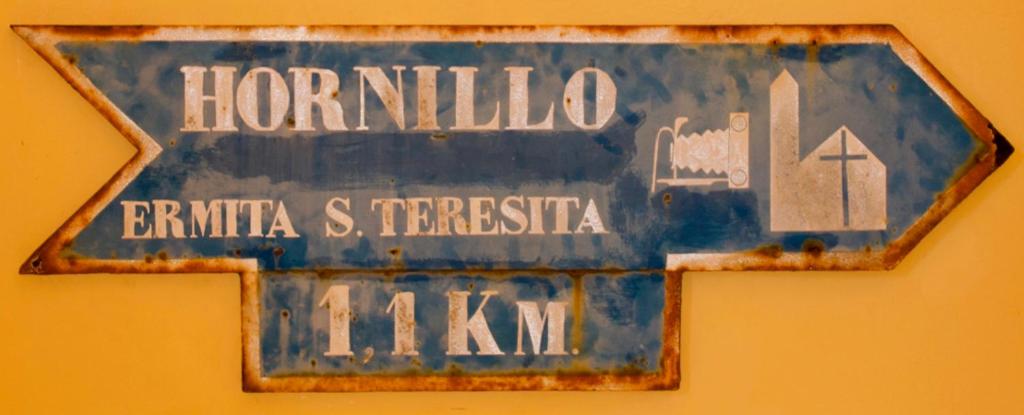 a blue street sign on a yellow wall at Refugio El Hornillo in San Pedro