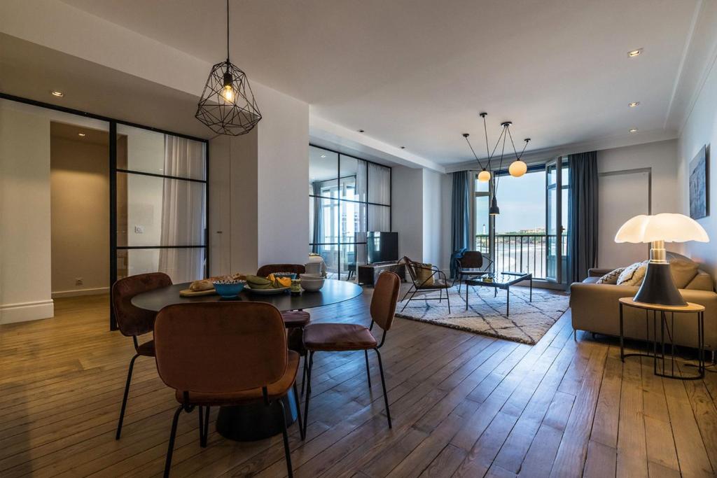a living room with a table and chairs and a couch at BEACHVIEW KEYWEEK Beachfront Renovated Apartment with Parking in Biarritz in Biarritz