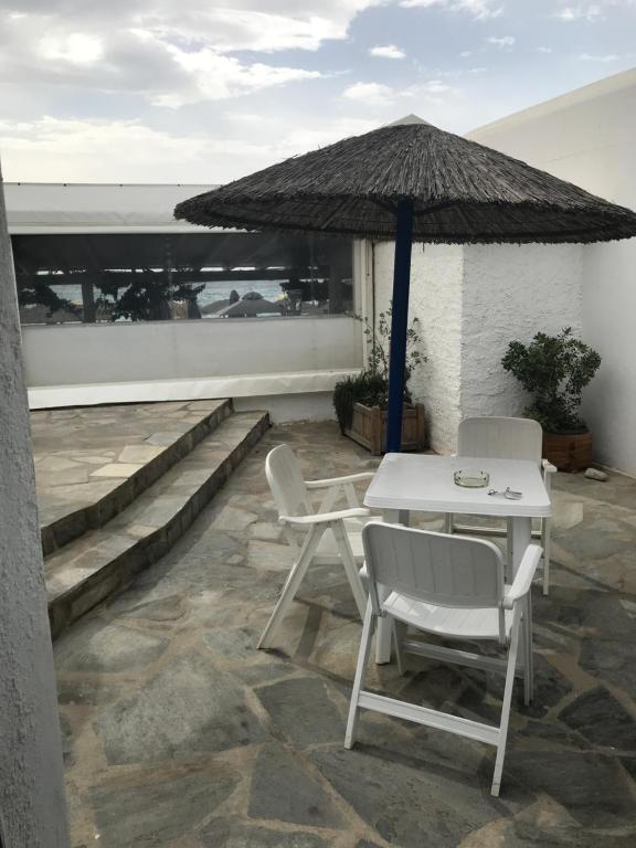 a patio with a table and chairs and an umbrella at Romantika in Platis Gialos
