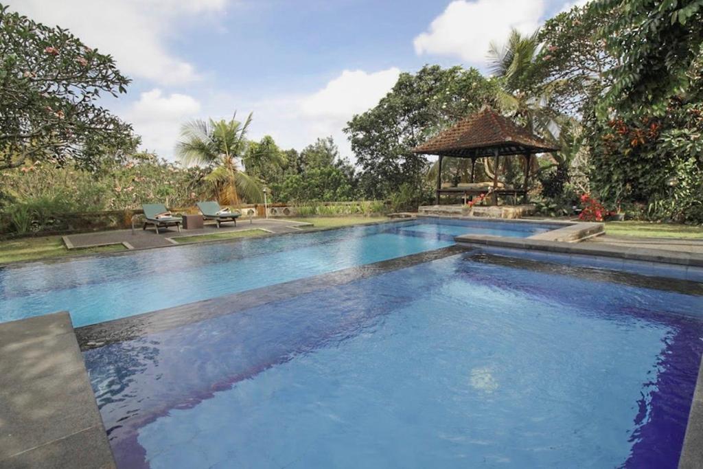a large swimming pool with a gazebo at Taman Indrakila in Ubud