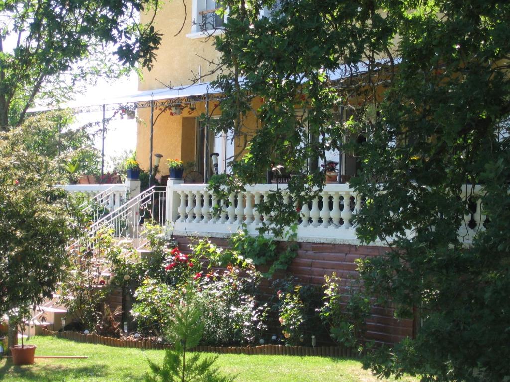 a white fence in front of a house with flowers at La Maison Jaune in Réalville