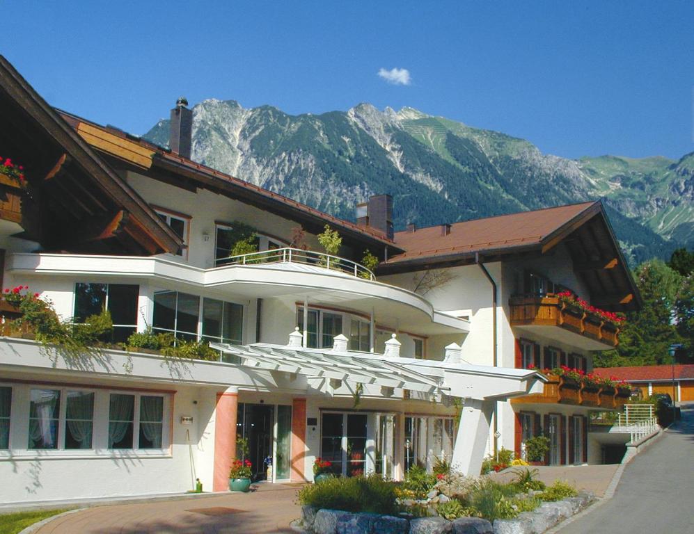 a large white building with mountains in the background at Ringhotel Nebelhornblick in Oberstdorf