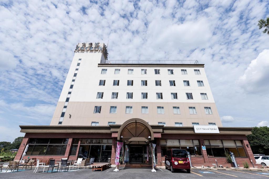 a large white building with a bus parked in front of it at Tabist Tsukuba Sky Hotel in Tsukuba