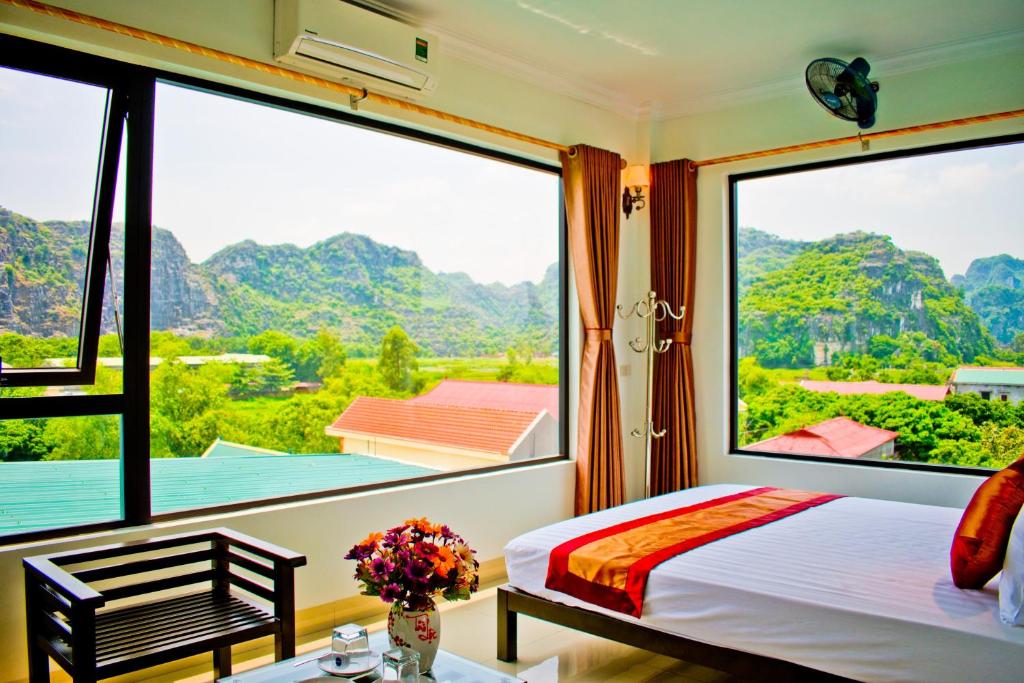 1 dormitorio con 1 cama y ventanas grandes en Trang An Mountain View Homestay en Ninh Binh