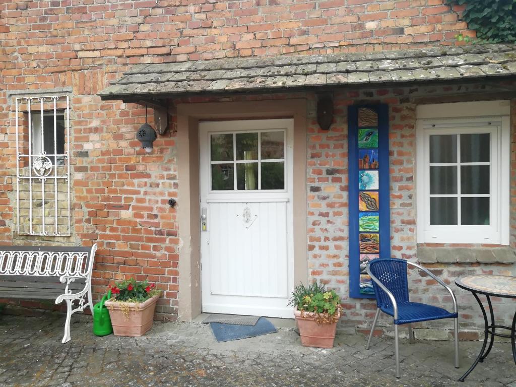 a brick house with a white door and a table and chairs at Ehemalige Bibliothek Apartment für 2 mit Küche Kamin Netflix Parken und Hofladen in Steinhöfel